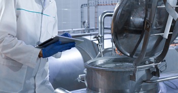 Inspector with Tablet Standing Over Large Steel Tank