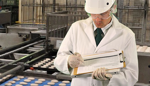 Man with clipboard in cookie manufacturing site.